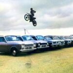 1978 A motorcycle rider performs a stunt by jumping over a line of parked vans at the Wrexham Wild West Festival
